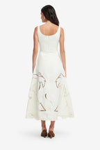 Woman wearing a white dress with palm tree designs on a white background