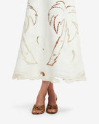 White dress with palm tree design worn by a person on a white background