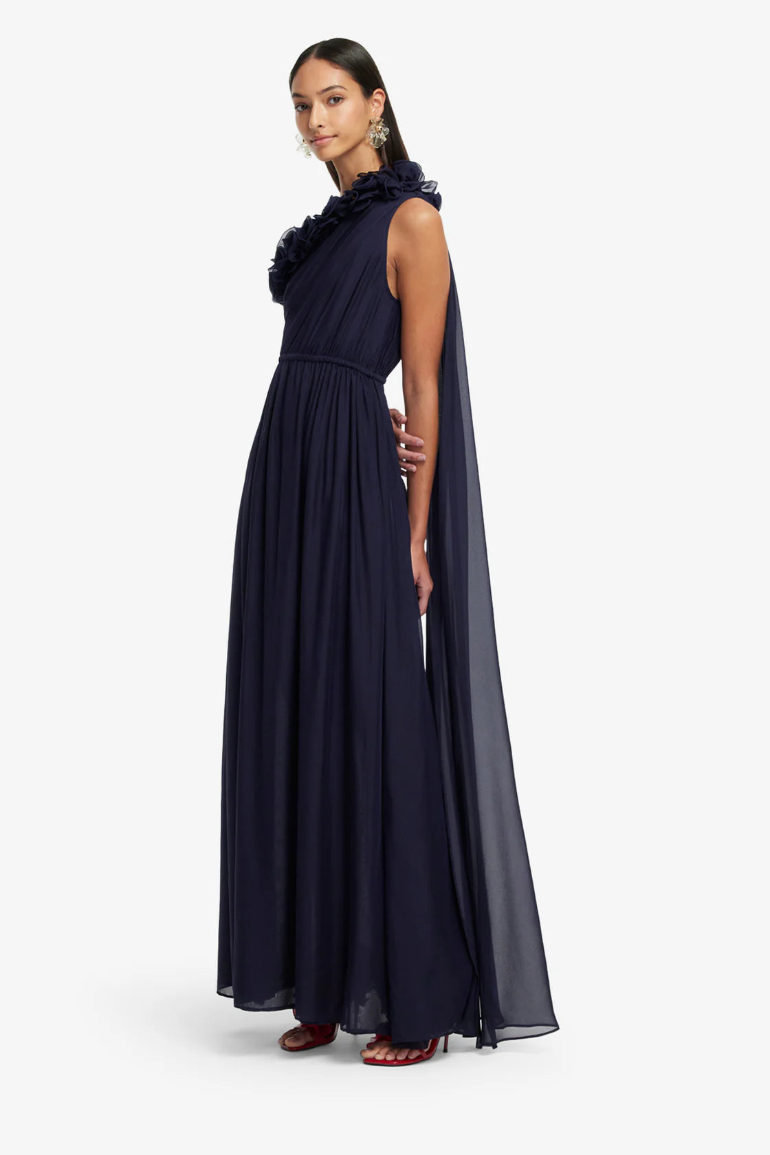 Woman wearing a long navy dress with a cape on a white background