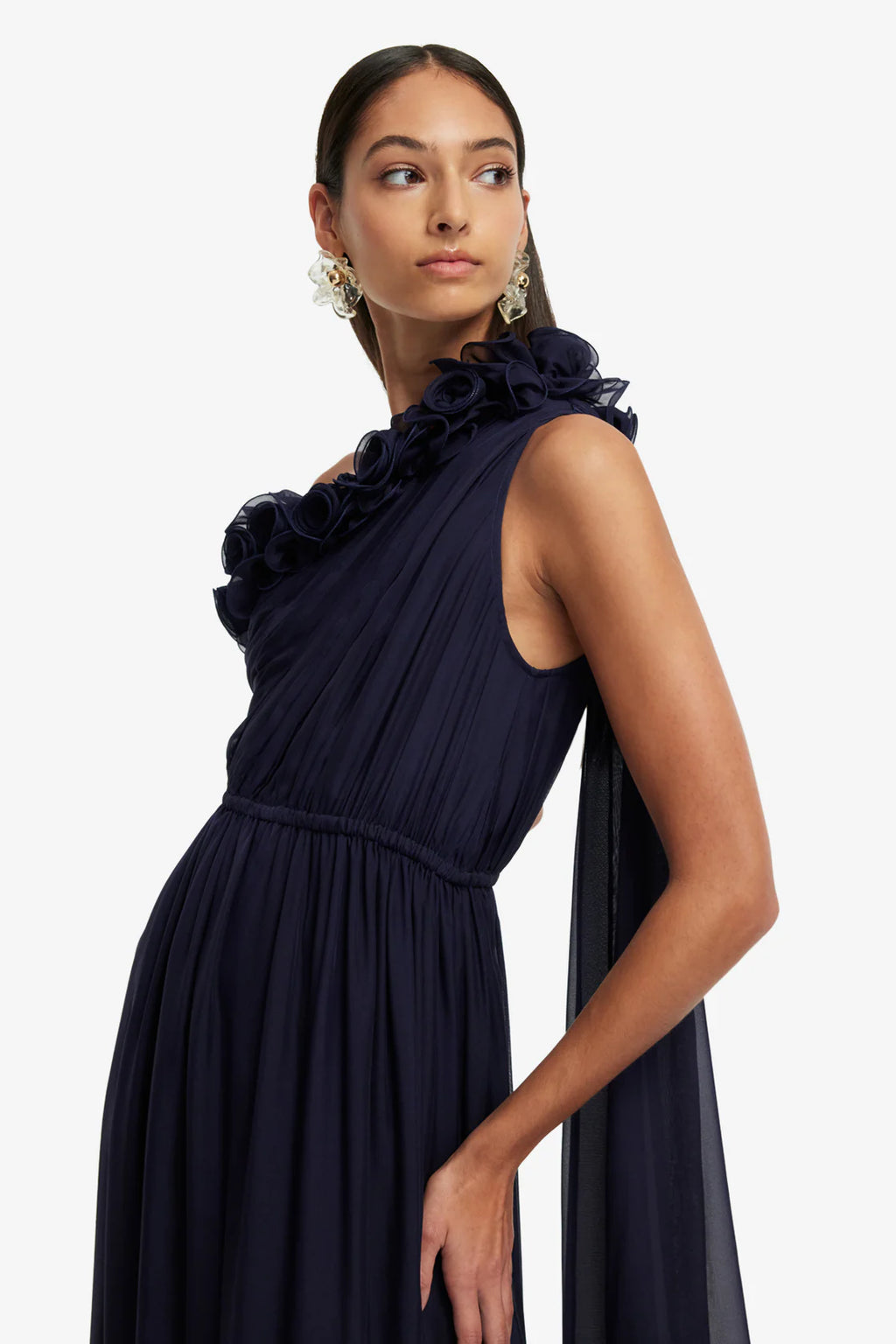 Woman wearing a navy blue dress with floral details on a white background