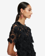 Woman wearing a black lace dress with red heart earrings on a white background