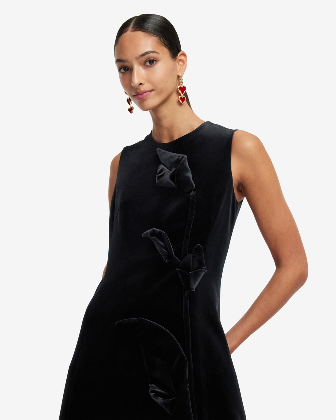 Woman wearing a black sleeveless dress with ruffled details on a white background