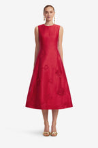 Woman wearing a red dress with floral patterns on a white background