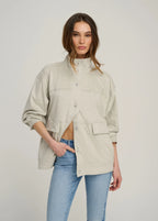 Woman wearing a beige jacket and blue jeans on a plain background