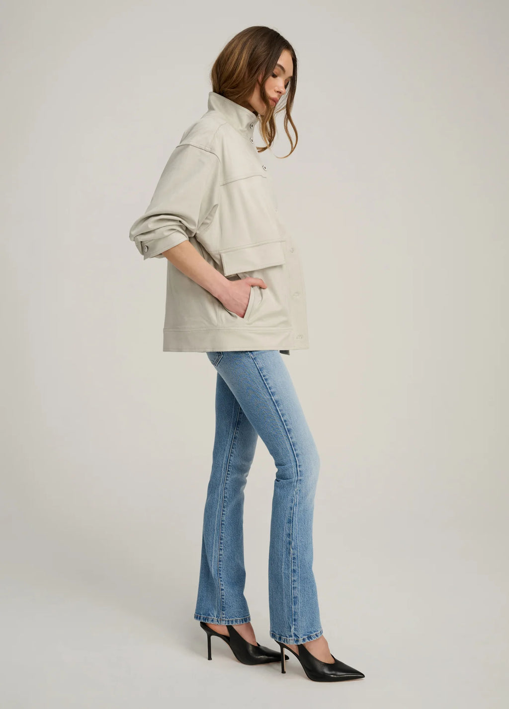 Woman wearing a beige jacket and blue jeans on a white background