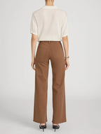 Person wearing a white shirt and brown pants on a light gray background