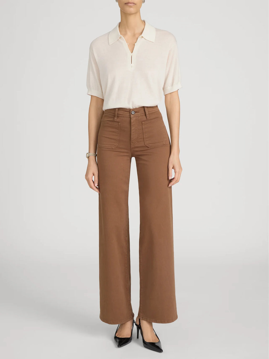 Person wearing a white blouse and brown pants on a plain background