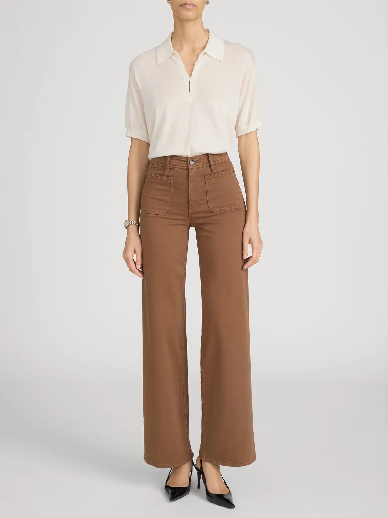 Person wearing a white blouse and brown pants on a plain background
