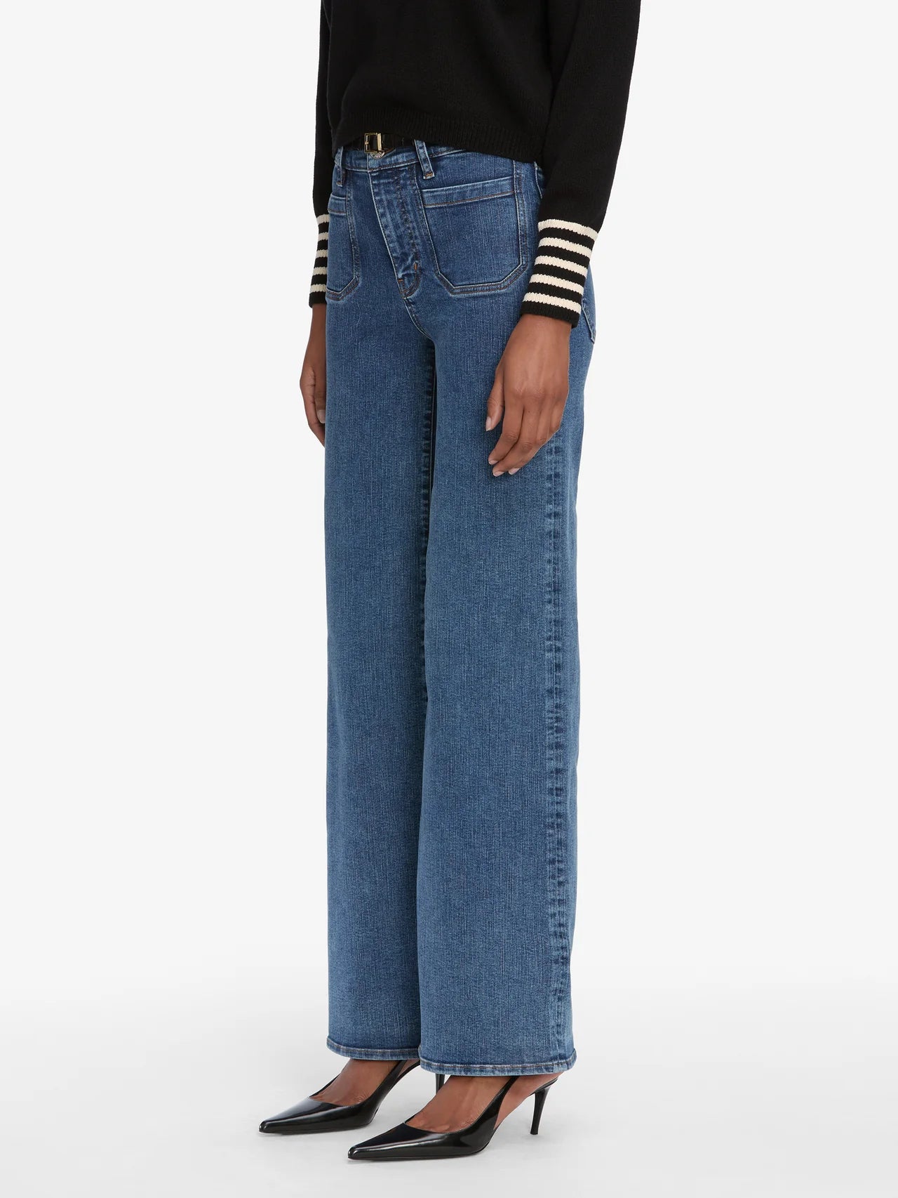 Person wearing blue jeans and black high-heeled shoes on a white background