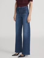 Person wearing blue jeans on a plain background
