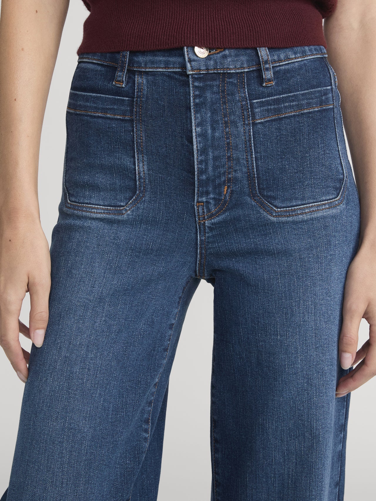 Blue jeans worn by a person on a plain background