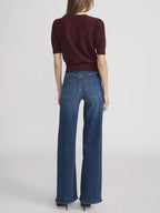 Person wearing a burgundy top and blue jeans on a light gray background