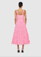 Woman wearing a pink dress with floral patterns on a light gray background