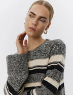 Woman wearing a black and white striped sweater against a plain background