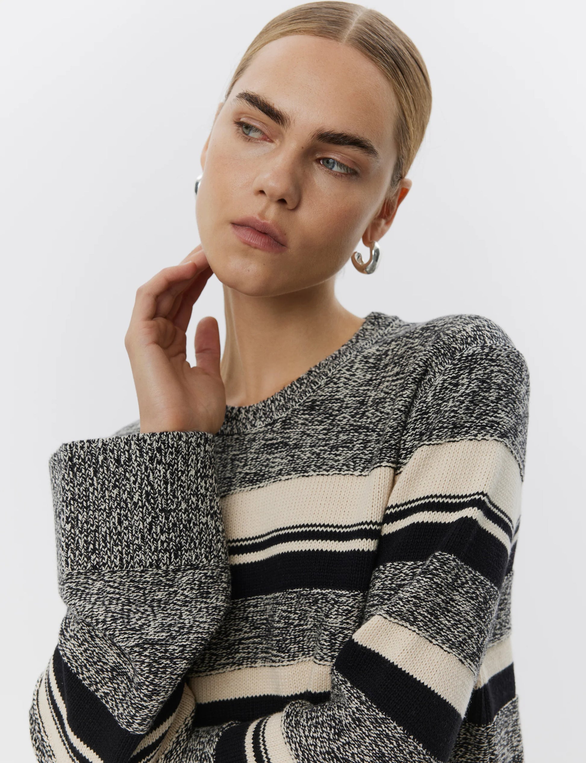 Woman wearing a black and white striped sweater against a plain background