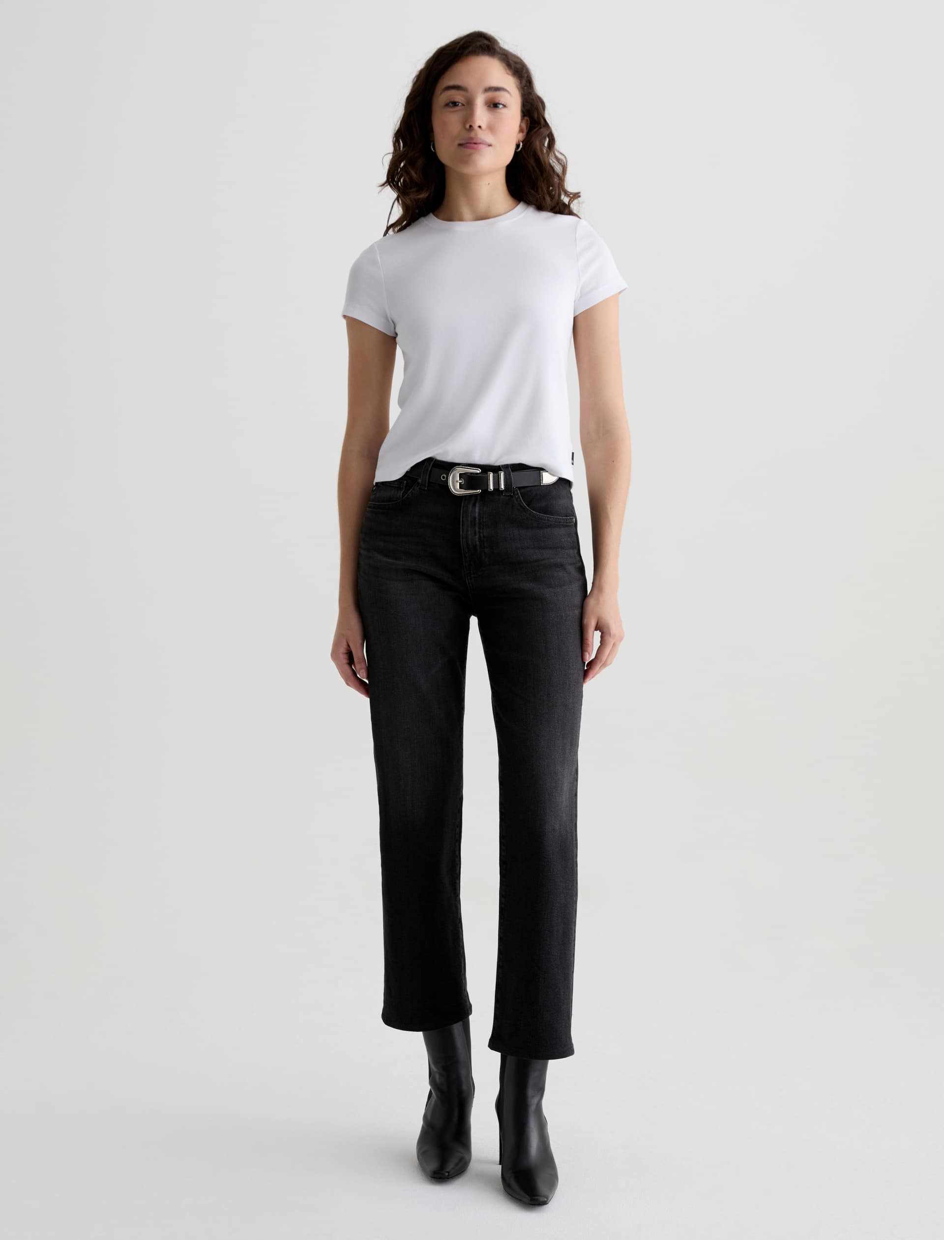 Woman wearing a white t-shirt and black jeans on a light gray background