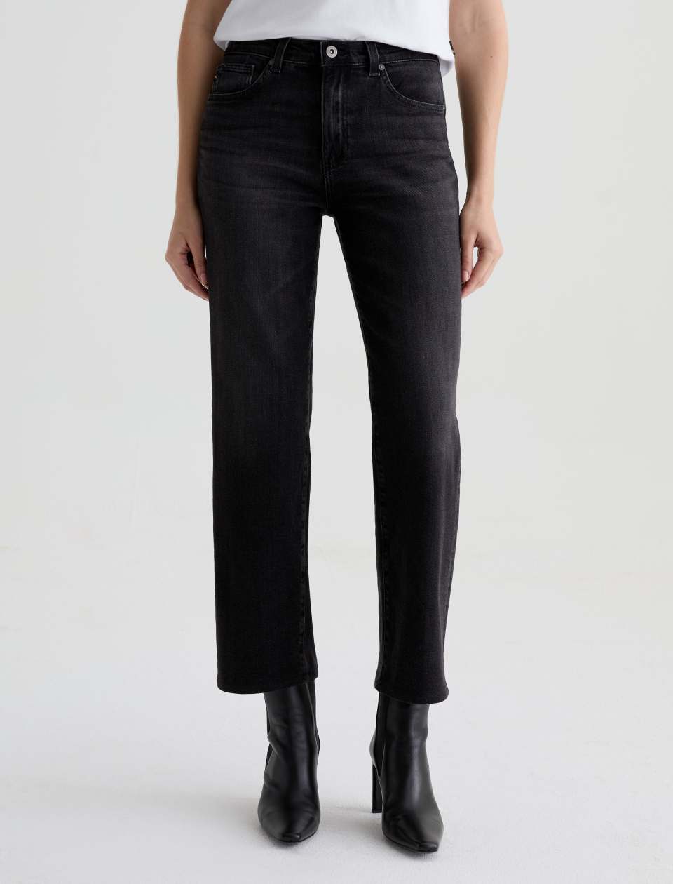 Person wearing black jeans and black boots on a white background