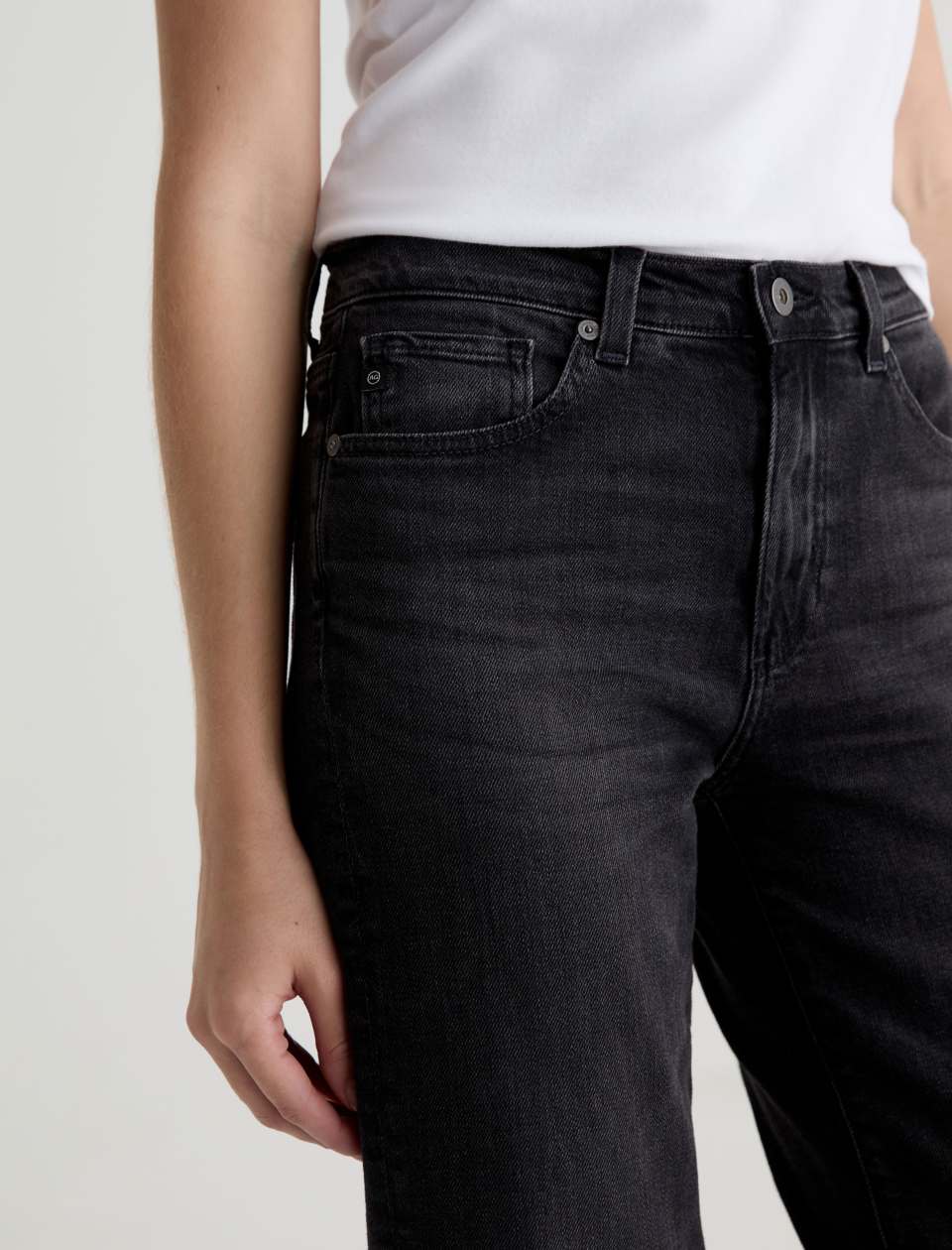 Person wearing black jeans and a white shirt on a plain background