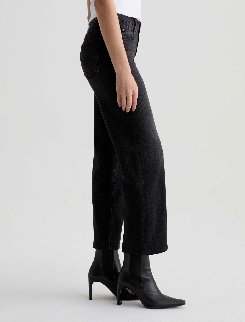 Person wearing black high-waisted jeans and black boots on a white background