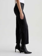 Person wearing black high-waisted jeans and black boots on a white background