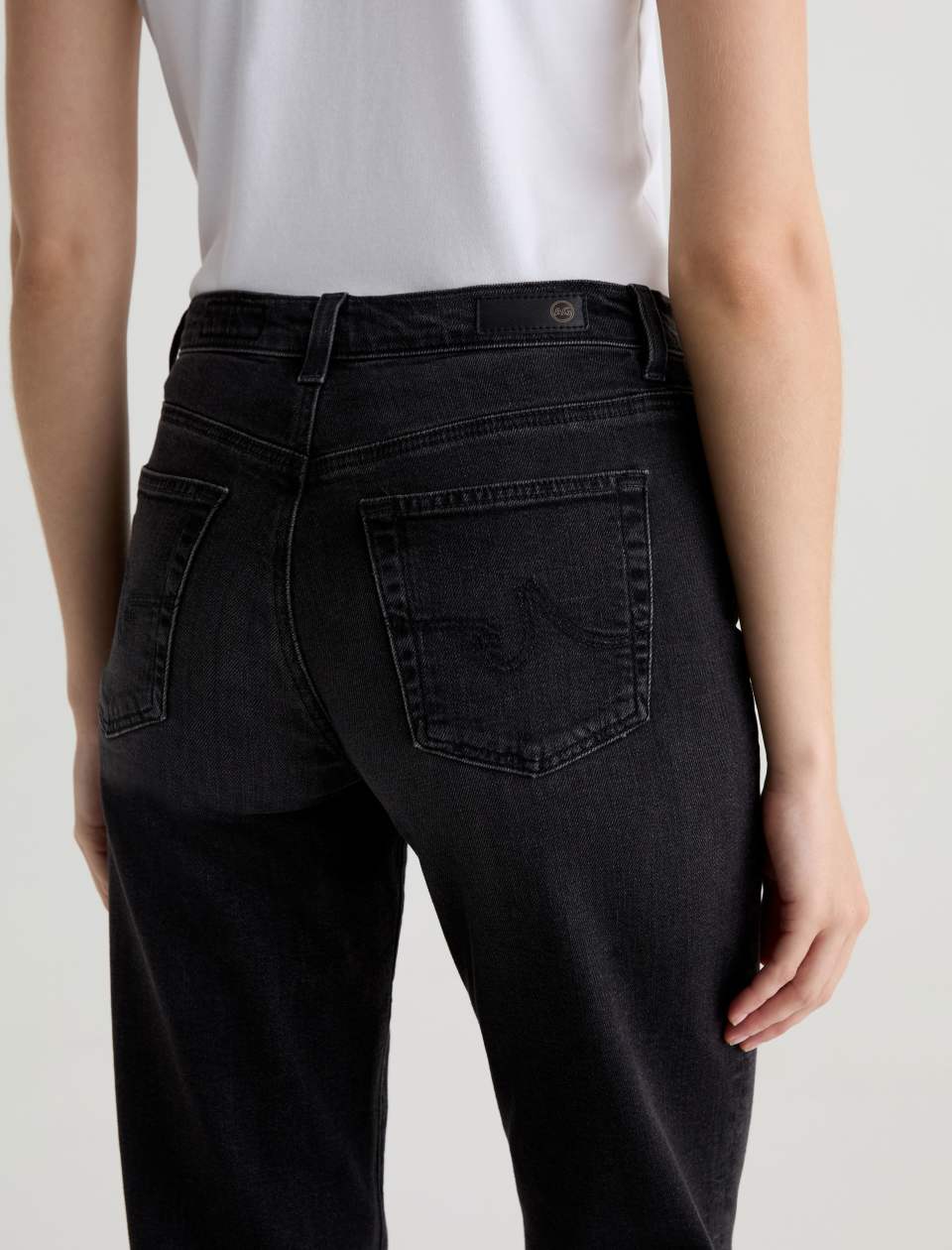 Person wearing black jeans on a plain background