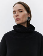 A person wearing a black turtleneck sweater made of wool.