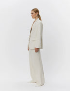 Woman wearing a beige suit standing against a white background