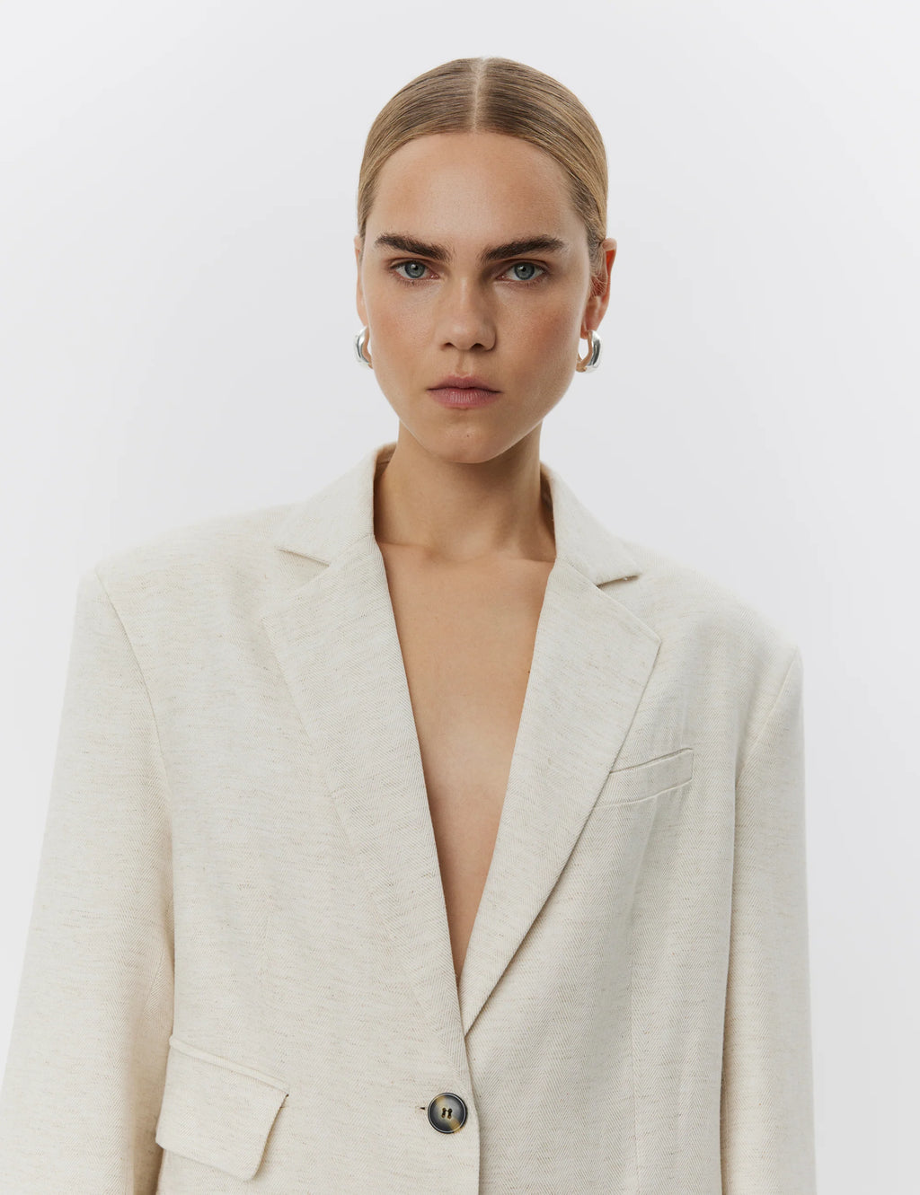 Person wearing a light-colored blazer against a plain background