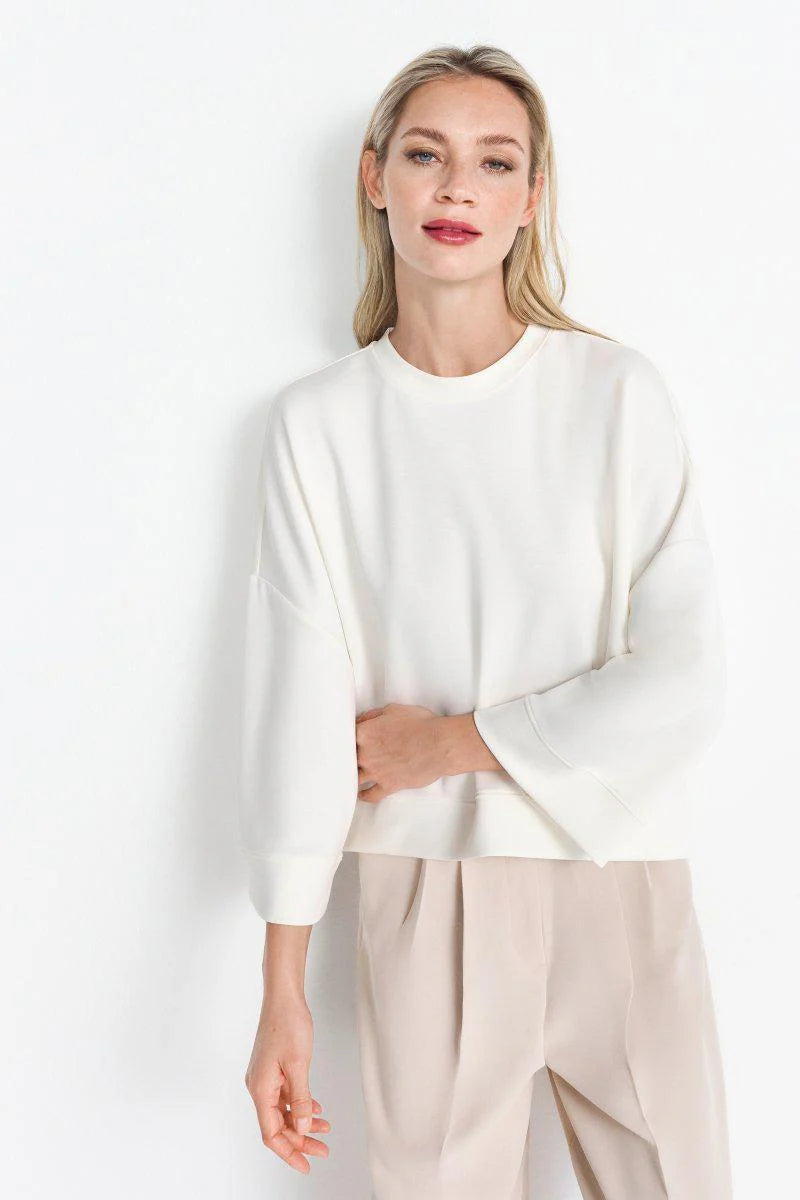 Woman wearing a rich and royal white sweater and beige pants against a white background shop online muse boutique hawthorn