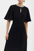 Black dress with short sleeves and a subtle cutout detail on a white background