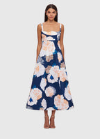 A woman wearing a navy midi dress with a floral rosebud print, featuring a fitted bodice and waist, and an A-line skirt with a structured crinoline hem.