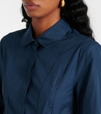 A close-up image of a woman wearing a navy blue long-sleeved shirt with a collar, featuring a concealed buttoned front and side slit pockets.