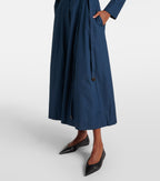 Person wearing a long navy coat on a white background