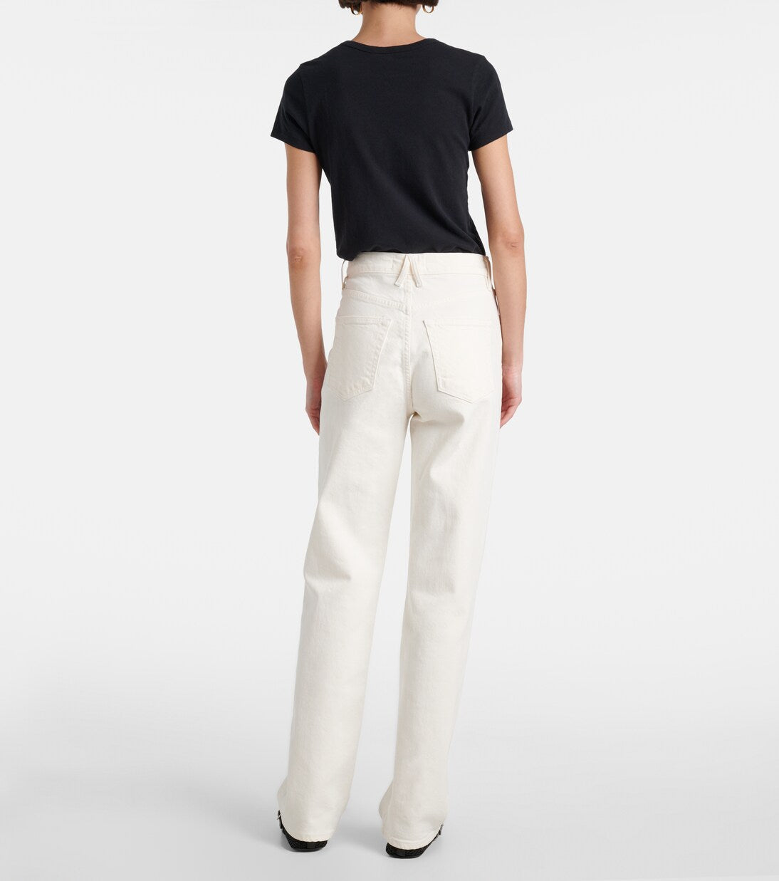 Person wearing a black t-shirt and white pants on a plain background