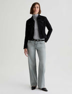 Person wearing a black jacket, gray turtleneck, and light gray jeans on a white background