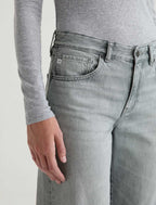 Person wearing light gray jeans and a matching long-sleeve shirt on a plain background