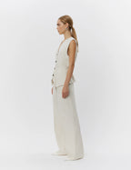 Woman wearing a beige vest and pants on a white background