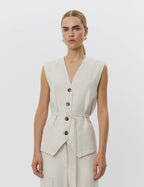 Woman wearing a light gray vest with buttons on a white background