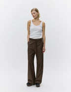 Woman wearing a white tank top and brown pants on a white background