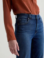 Person wearing blue jeans and a brown shirt on a white background