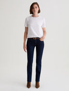 Person wearing a white t-shirt and dark blue jeans on a light gray background