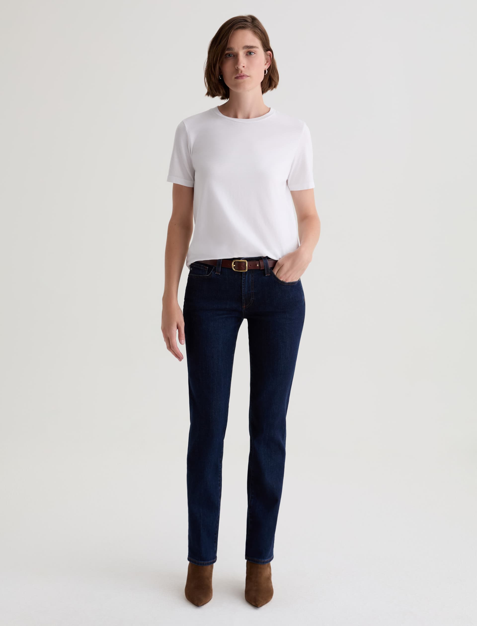 Person wearing a white t-shirt and dark blue jeans on a light gray background