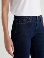 Person wearing dark blue jeans and a white shirt on a light background