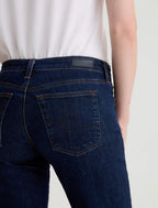 Person wearing dark blue jeans on a plain background