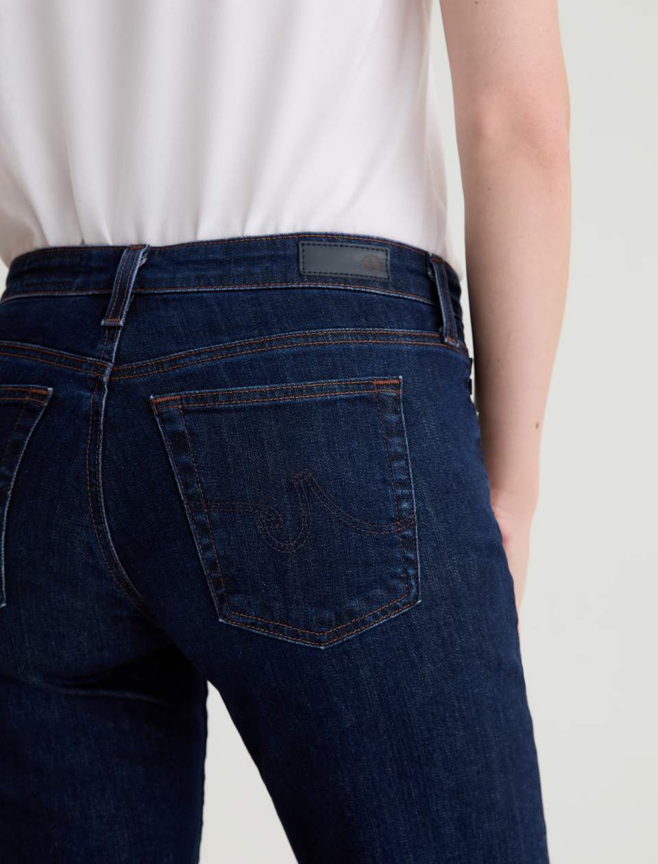 Person wearing dark blue jeans on a plain background