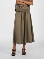 Person wearing a long olive green dress on a white background