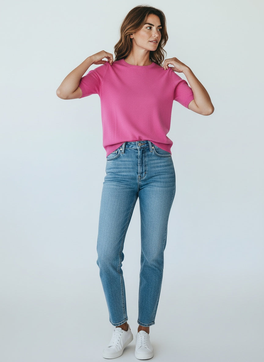 Woman wearing a pink t-shirt and blue jeans against a white background