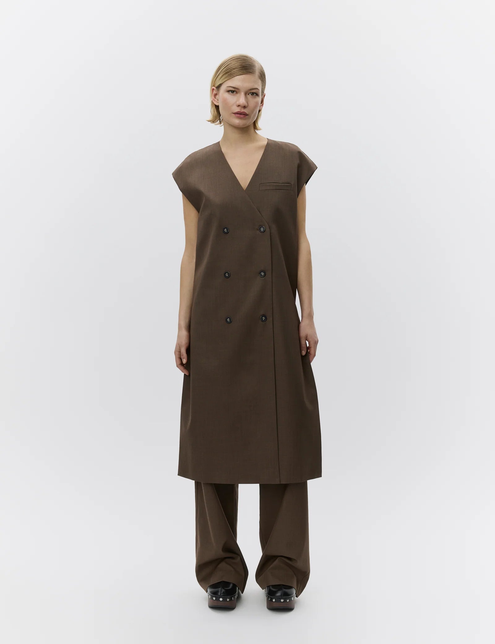 Woman wearing a brown sleeveless dress with a V-neckline on a white background