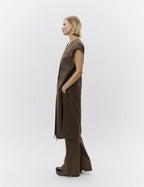 Woman wearing a brown sleeveless top and wide-leg pants on a white background