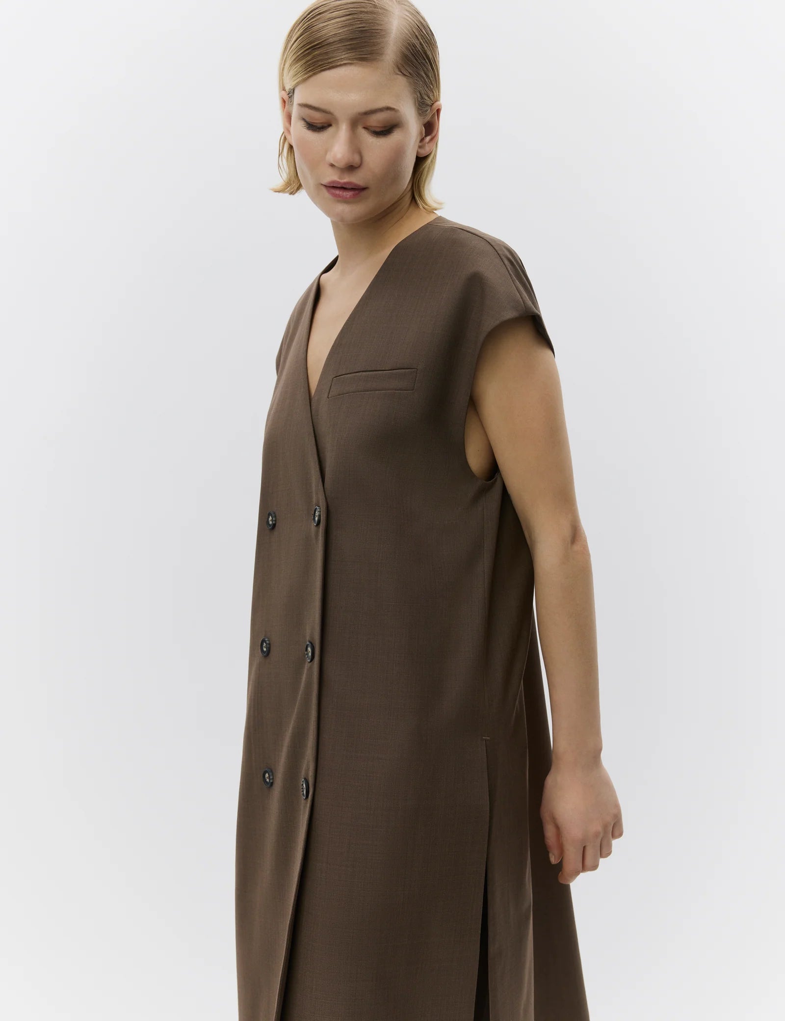 Woman wearing a brown sleeveless dress against a white background